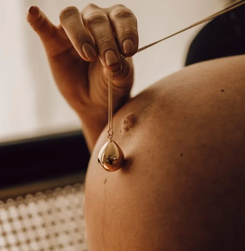 Bola de grossesse en forme de goutte porté sur le ventre d’une femme enceinte, bijou de maternité apaisant et symbolique