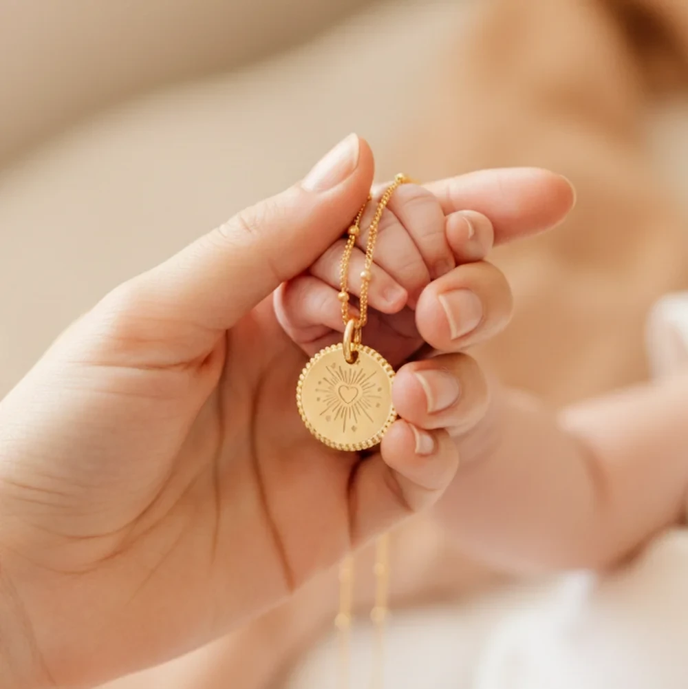 Main tenant un pendentif gravé personnalisé, bijou symbolique représentant un lien d’amour entre parent et enfant